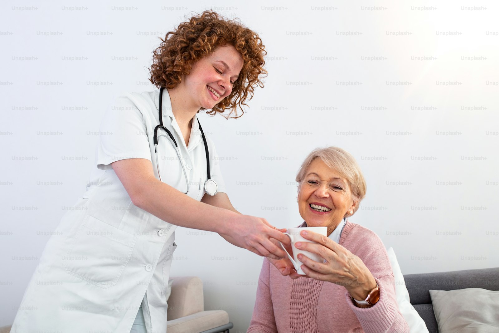 A caregiver sharing tea with a happy senior woman at home